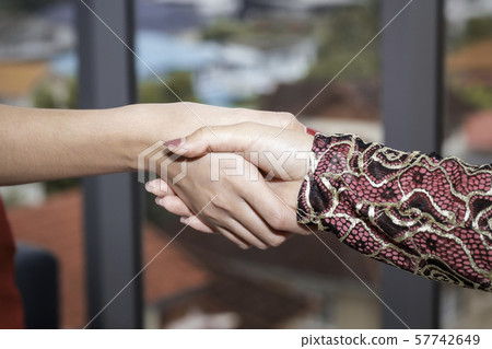 Young beautiful Muslim woman shaking hand with Young beautiful Muslim woman shaking hand with 57742649