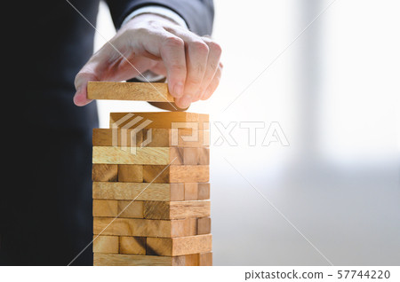 Businessman arranging wood block and stacking as Businessman arranging wood block and stacking as 57744220