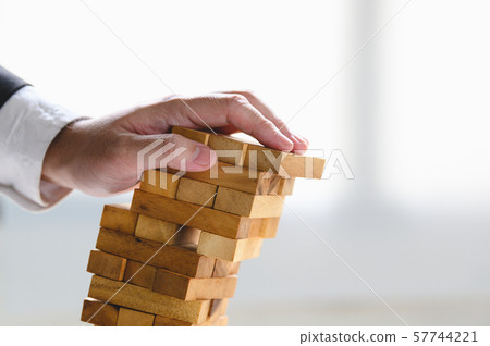 Businessman collapsing stacked tower wood block by Businessman collapsing stacked tower wood block by 57744221
