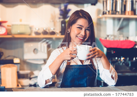 Asian female barista making cup of coffee. Young 57744783