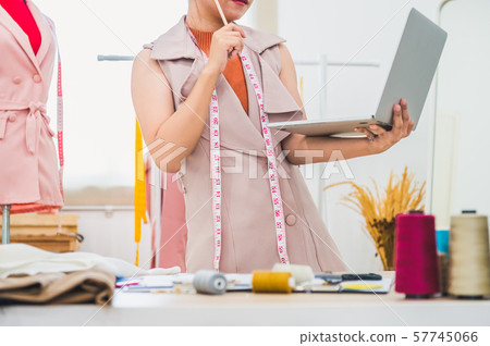 Happy Asian female fashion designer working in 57745066