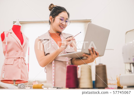 Happy Asian female fashion designer working in 57745067