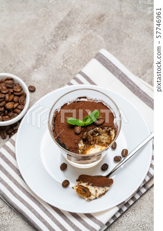 Portion of Classic tiramisu dessert in a glass cup on concrete background Portion of Classic tiramisu dessert in a glass cup on concrete background 57746961