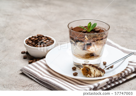 Portion of Classic tiramisu dessert in a glass cup on concrete background 57747003