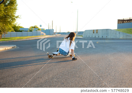 Young girl having fun with skateboard on the road. Young girl having fun with skateboard on the road. 57748029