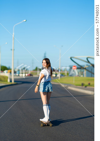 stylish girl in white stockings ride on longboard 57748031