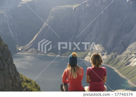 Two sitting women are looking for mountain lake Two sitting women are looking for mountain lake 57748374