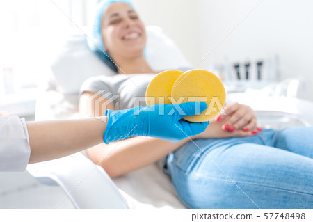 the hand of the beautician holds the massage pad 57748498