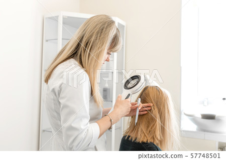 The doctor trichologist dermatologist examines the The doctor trichologist dermatologist examines the 57748501