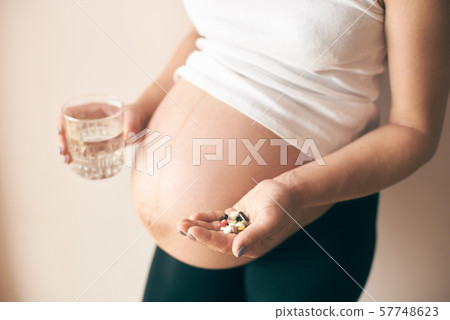 View from side of pregnant woman taking vitamins 57748623