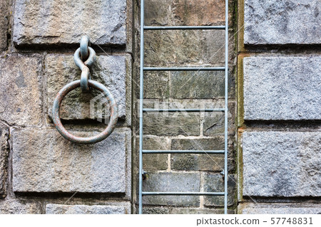 metal ladder and a ring on a stone wall. metal ladder and a ring on a stone wall. 57748831