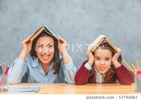Cheerful mom and daughter on a gray background. During this, on the head of my mother and daughter Cheerful mom and daughter on a gray background. During this, on the head of my mother and daughter 57748862