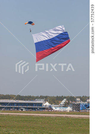 A man flying in the sky with opened parachute and russian flag - getting closer to the ground A man flying in the sky with opened parachute and russian flag - getting closer to the ground 57752439