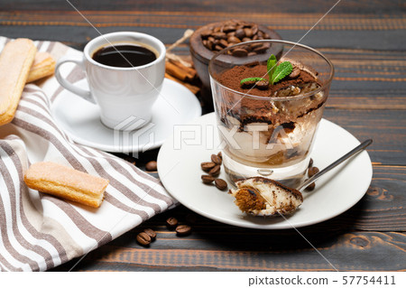 Portion of Classic tiramisu dessert in a glass, cup of coffee and savoiardi cookies on wooden Portion of Classic tiramisu dessert in a glass, cup of coffee and savoiardi cookies on wooden 57754411