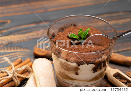 Portion of Classic tiramisu dessert in a glass and savoiardi cookies on wooden background 57754485