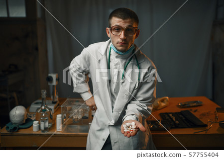 Male psychiatrist in lab coat shows sedative pills 57755404