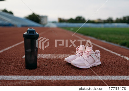 Sport shoes and bottle of water on stadium, nobody Sport shoes and bottle of water on stadium, nobody 57755478