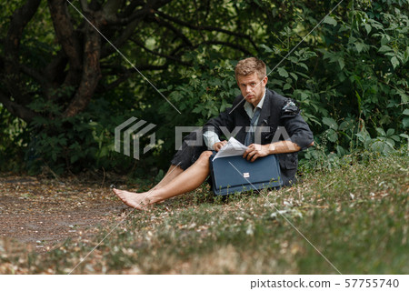 Businessman sitting on the ground on desert island 57755740