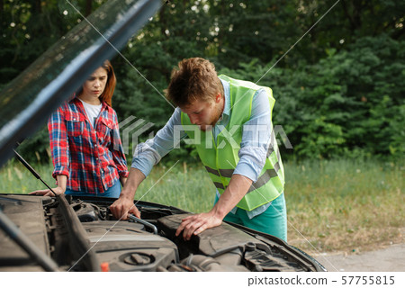 Couple at the opened hood on road, car breakdown Couple at the opened hood on road, car breakdown 57755815