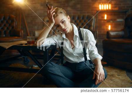 Woman sitting on the floor with whiskey and cigar 57756174