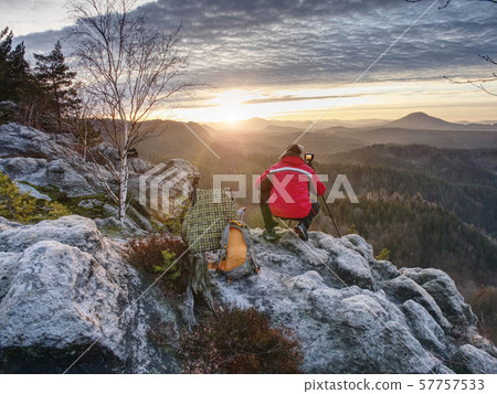 Alone hiker photographer in warm red jacket stand 57757533