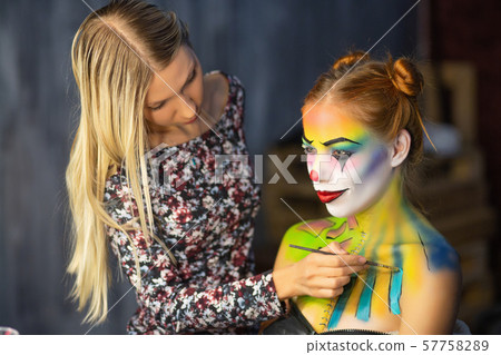 The artist applies body art to a charming woman. 57758289