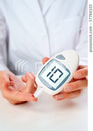 Photo of man's hand with glucometer with inscription ten in studio Photo of man's hand with glucometer with inscription ten in studio 57768103