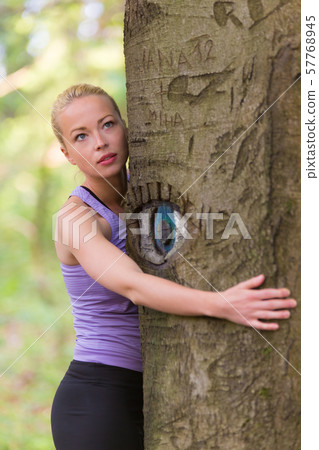 Young woman hugging a tree. Young woman hugging a tree. 57768945