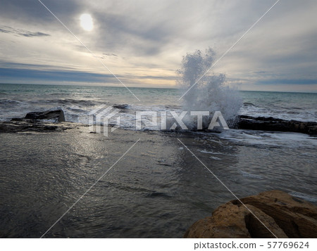 Wave breaks on the rocks. 57769624