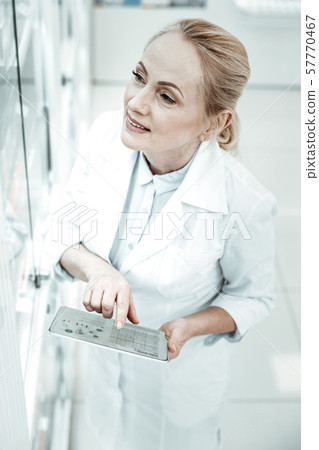 A respectful female pharmacy owner checking up medicine assortment. 57770467