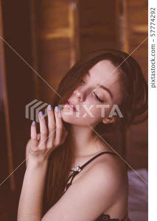Young attractive woman with long dark hair in black lace lingerie on a bed. Boudoir photo of a young girl 57774292