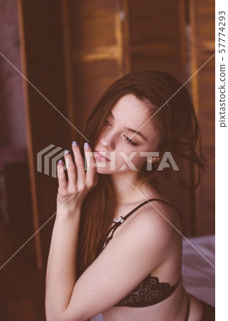 Young attractive woman with long dark hair in black lace lingerie on a bed. Boudoir photo of a young girl 57774293