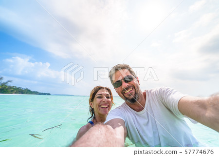 Happy man and woman taking selfie in tropical 57774676