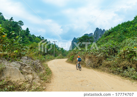 Woman riding mountain bike on dirt road in scenic 57774707