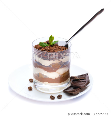 Classic tiramisu dessert in a glass cup on the plate and pieces of chocolate on white background 57775354
