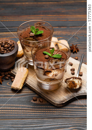 Portion of Classic tiramisu dessert in a glass and savoiardi cookies on wooden background Portion of Classic tiramisu dessert in a glass and savoiardi cookies on wooden background 57775363