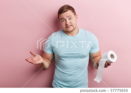 man holding toliet tissue and looking at the camera with clueless expression 57775650