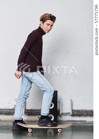 cool handsome man in stylish sweater stands on his skateboard 57775796