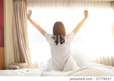 Woman stretching in bed after waking up, back Woman stretching in bed after waking up, back 57776037
