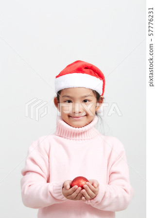 Girl holding a red christmas ball in sweater and Girl holding a red christmas ball in sweater and 57776231