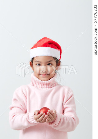 Girl holding a red christmas ball in sweater and Girl holding a red christmas ball in sweater and 57776232