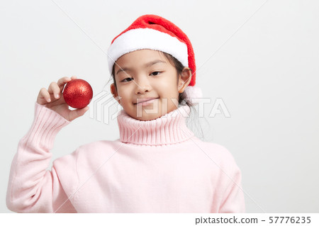 Girl holding a red christmas ball in sweater and Girl holding a red christmas ball in sweater and 57776235