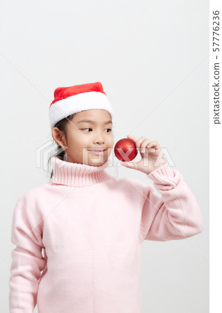 Girl holding a red christmas ball in sweater and Girl holding a red christmas ball in sweater and 57776236
