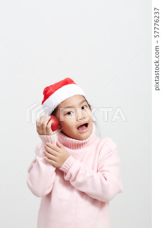 Girl holding a red christmas ball in sweater and Girl holding a red christmas ball in sweater and 57776237