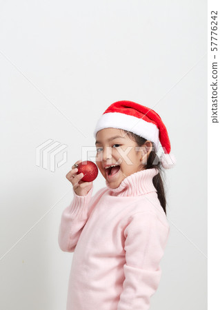 Girl holding a red christmas ball in sweater and Girl holding a red christmas ball in sweater and 57776242