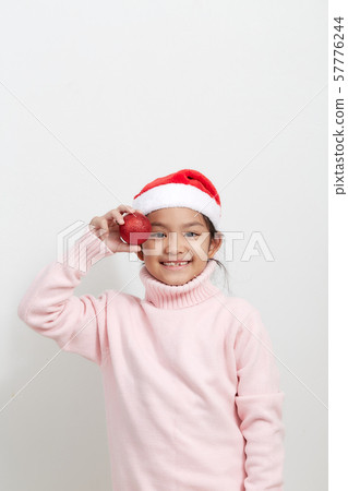 Girl holding a red christmas ball in sweater and Girl holding a red christmas ball in sweater and 57776244