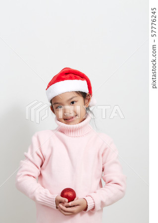 Girl holding a red christmas ball in sweater and Girl holding a red christmas ball in sweater and 57776245