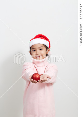 Girl holding a red christmas ball in sweater and Girl holding a red christmas ball in sweater and 57776247