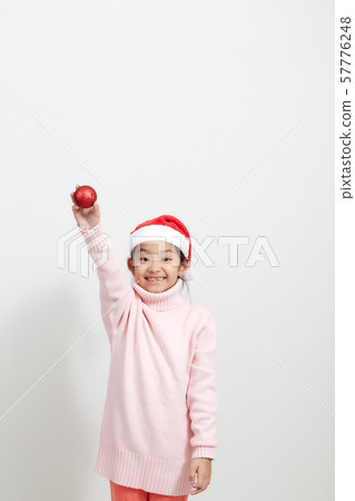 Girl holding a red christmas ball in sweater and Girl holding a red christmas ball in sweater and 57776248