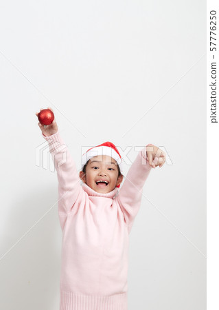 Girl holding a red christmas ball in sweater and Girl holding a red christmas ball in sweater and 57776250